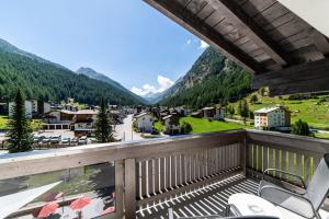 a balcony with a view of a town and mountains at Hotel Kristall-Saphir Superior in Saas-Almagell