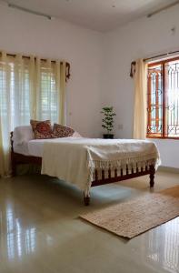 a bed in a white room with a window at Heligans Yard - LADIES ONLY in Varkala