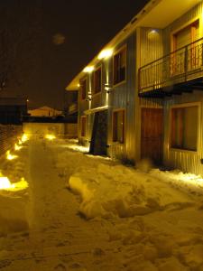 a snow covered street in front of a building with lights at Ukurj Apartamentos in Ushuaia