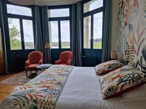 una camera da letto con un letto, due sedie e finestre di Domaine de l'Oie Rouge a Les Rosiers