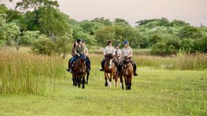 um grupo de pessoas montando cavalos em um campo em Unyati Safari Lodge em Hectorspruit