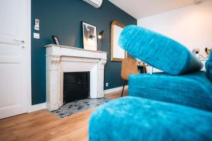 ein blaues Sofa im Wohnzimmer mit Kamin in der Unterkunft Le Blue Berry • Élégant & Fonctionnel • Proche Gare in Châteauroux