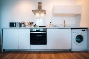 a white kitchen with a dishwasher and a washer at Le Blue Berry • Élégant & Fonctionnel • Proche Gare in Châteauroux