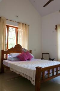 Heligans Yard - LADIES ONLY في فاركَالا: غرفة نوم بسرير خشبي في غرفة مع نافذة