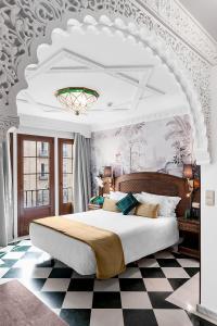 a bedroom with a large bed and a checkered floor at Hotel Boutique Las Almenas in Granada