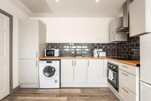 a kitchen with white cabinets and a washer and dryer at Bright 1 Bedroom Apartment in Central Doncaster in Doncaster