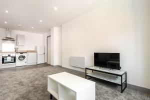 a white living room with a table and a tv at Comfortable 1 Bedroom Apartment in Central Doncaster in Doncaster