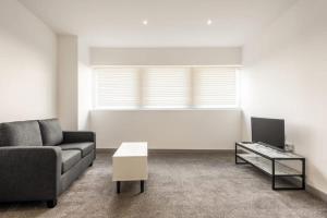 a living room with a couch and a tv at Comfortable 1 Bedroom Central Doncaster Apartment in Doncaster