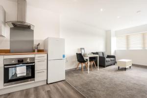 eine Küche und ein Wohnzimmer mit einem Kühlschrank und einem Tisch in der Unterkunft Comfortable 1 Bedroom Central Doncaster Apartment in Doncaster