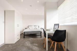 een slaapkamer met een bed, een bureau en stoelen bij Comfortable Studio Apartment in Central Doncaster in Doncaster