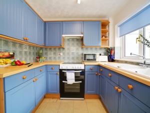 a blue kitchen with blue cabinets and a sink at Mor Gwyns in Port Isaac