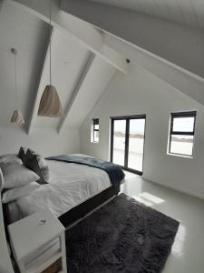 a white bedroom with a bed and a rug at C-Rock Holiday Home Jacobs Bay in Jacobs Bay