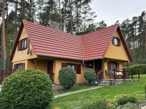una pequeña casa amarilla con techo rojo en Chata u lesa, en Přeštice