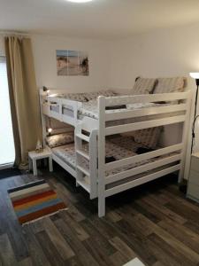 2 weiße Etagenbetten in einem Zimmer mit Holzböden in der Unterkunft FEWO Kutsch Watt Nr.3 in Cuxhaven