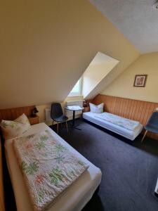 a attic room with two beds and a table and chairs at Pension Schmidt in Bad Kösen