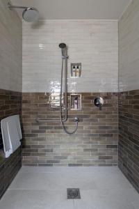 a shower in a bathroom with brown tiles at The Carnarvon Arms in Newbury