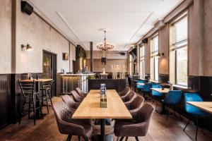 a restaurant with wooden tables and chairs and windows at Hotel Brasserie Smits in Wemeldinge