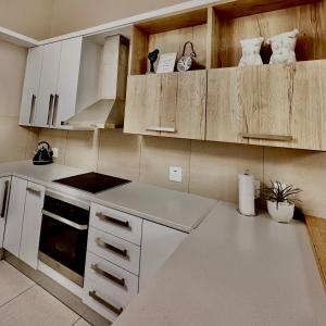 una cocina con electrodomésticos blancos y armarios de madera en Upmarket apartment in the heart of Windhoek, en Windhoek