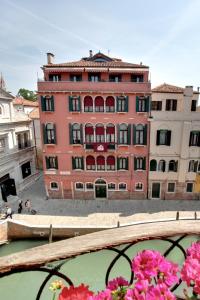 a large red building in front of a body of water at Palazzo Schiavoni Suite-Apartments in Venice