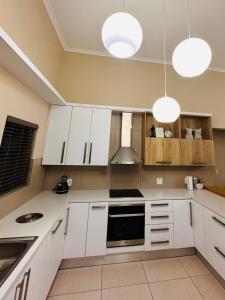 una cocina con armarios blancos y 2 luces en Upmarket apartment in the heart of Windhoek, en Windhoek