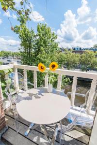 een tafel en stoelen op een balkon met een vaas met zonnebloemen bij Amstel Corner Hotel in Amsterdam