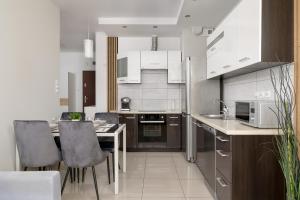 cocina con armarios blancos, mesa y sillas en Podgórze Air-Conditioned Family Apartment with Parking by Renters, en Cracovia
