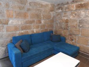 a blue couch in a room with a brick wall at Ferienwohnungen am Hauptplatz in Pirna