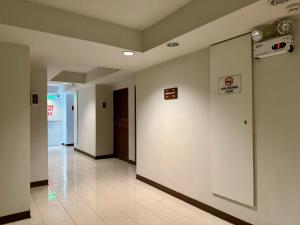 a hallway with white walls and a tile floor at Pas Cher Hotel de Bangkok in Bangkok
