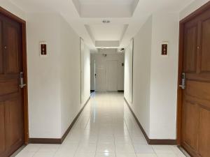 an empty hallway with white walls and wooden doors at Pas Cher Hotel de Bangkok in Bangkok