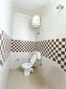 a bathroom with a toilet with a checkered wall at Roomshala 172 Hotel Blue Moon - Satya Niketan in New Delhi