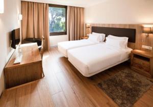 a hotel room with two beds and a desk at Hotel Eden Park by Brava Hoteles in Riudellots de la Selva