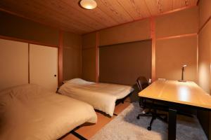 a room with two beds and a desk and a table at 貸切型の民泊です間取り2LDK無料駐車場有り全館完全禁煙です屋外喫煙所無し福井駅西口恐竜広場から徒歩約14分距離約1100m in Fukui