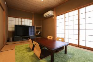 a living room with a wooden table and a television at 貸切型の民泊です間取り2LDK無料駐車場有り全館完全禁煙です屋外喫煙所無し福井駅西口恐竜広場から徒歩約14分距離約1100m in Fukui