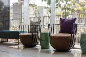 dwa krzesła z poduszkami siedzące w pokoju z oknem w obiekcie S&E Hotel w mieście Tainan