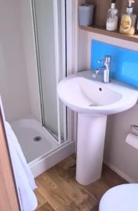 een badkamer met een witte wastafel en een douche bij Cosy, coastal themed Holiday Home, Rockley Park, Poole, Dorset in Poole