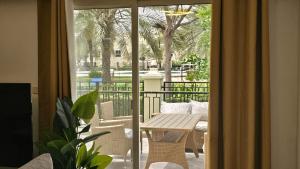 Luxury villa 4 bedroom with pool access في رأس الخيمة: باب زجاجي منزلق مع طاولة وكراسي على شرفة
