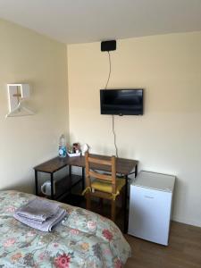 a bedroom with a bed and a desk with a television at L-Houses in Dagenham