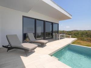 a patio with two chairs and a swimming pool at Hermosa Bay Oceanview Villa in Boca Chica