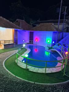 uma piscina à noite com luzes coloridas em ASHRAMAM HEALTH RESORT em Kattappana