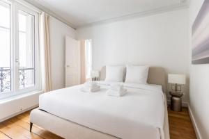 um quarto branco com uma grande cama branca e uma janela em Tour Eiffel - Invalides - Rénové em Paris