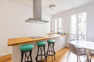 uma cozinha com um balcão com bancos e uma mesa em Tour Eiffel - Invalides - Rénové em Paris