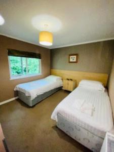 1 dormitorio con 2 camas y ventana en Mariners Lodge en Saint Minver