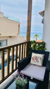 a chair on a balcony with a pillow and flowers at *NEW* BEACHFRONT APARTMENT SEA VIEW in Pefkohori