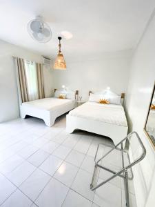 Cette chambre blanche comprend deux lits et une chaise. dans l'établissement Caleo Boracay Island Station 3, à Boracay