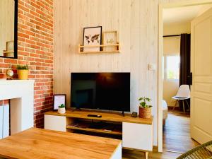 a living room with a television and a brick wall at Gîte Clair de Lune in Monts-sur-Guesnes