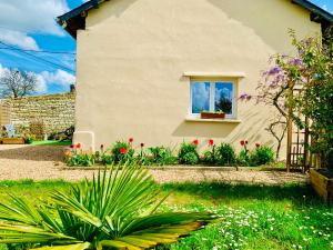 dom z oknem z kwiatami na dziedzińcu w obiekcie Gîte Clair de Lune w mieście Monts-sur-Guesnes