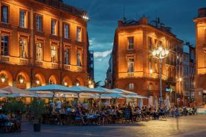 a group of people sitting at tables in front of buildings at *T2*Vue Garonne*Piscine*Garage* in Toulouse