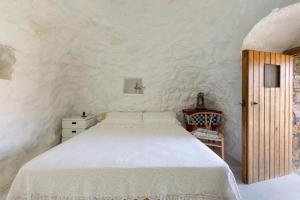 een slaapkamer met een wit bed in een kamer bij Trullo Salento in Corigliano dʼOtranto