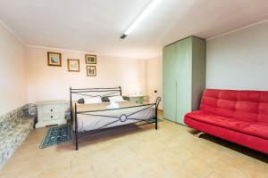 a bedroom with a bed and a red couch at Casa Vacanza Olmi in Capitana
