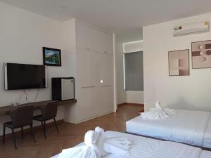1 dormitorio con 2 camas, escritorio y TV en BOPHAMANSION en Phumĭ Ŏng Char